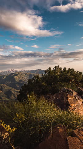 Slider timelapse of rocky landscape with distant snowy peaks and moving clouds at sunset