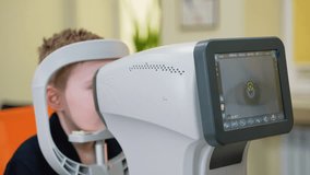 Young boy undergoing autorefractor eye exam at ophthalmology clinic - Powered by Shutterstock - Get 15% off with code: PIKWIZARD15