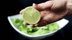 Splash of lime juice close up in slow motion. Hand squeezing half of a fresh lime on a black background. - Powered by Shutterstock - Get 15% off with code: PIKWIZARD15