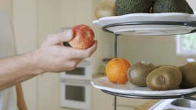 Man grabs fresh fruit from a bowl on kitchen counter. Natural light highlights healthy lifestyle and clean home interior. - Powered by Shutterstock - Get 15% off with code: PIKWIZARD15