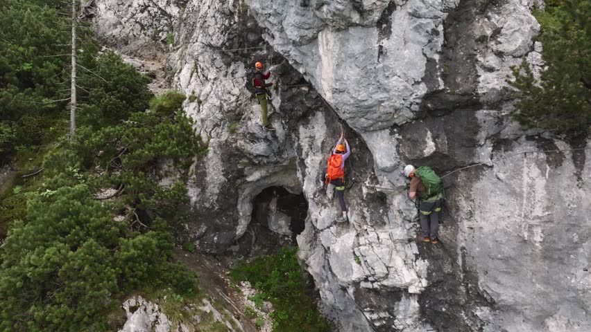 Group of climbers on a route, on a rock with belay via ferrata. Drone view of people in equipment