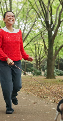 Happy, nature and woman running with dog for pet care, exercise or morning activity in forest. Smile, leash and Japanese female person with beagle puppy for outdoor health, wellness or adventure.