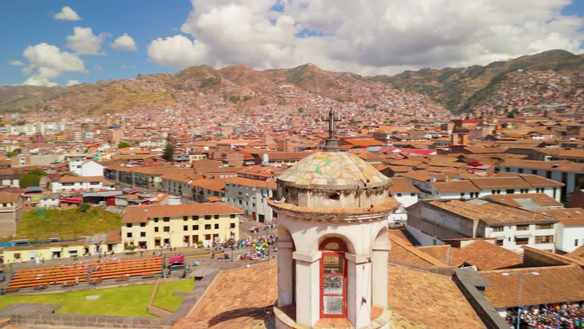 Aerial parallax shot of the Qorikancha Temple in Cusco, Peru, highlights the iconic Inca stonework, colonial architecture, and the surrounding cityscape nestled in the Andes.