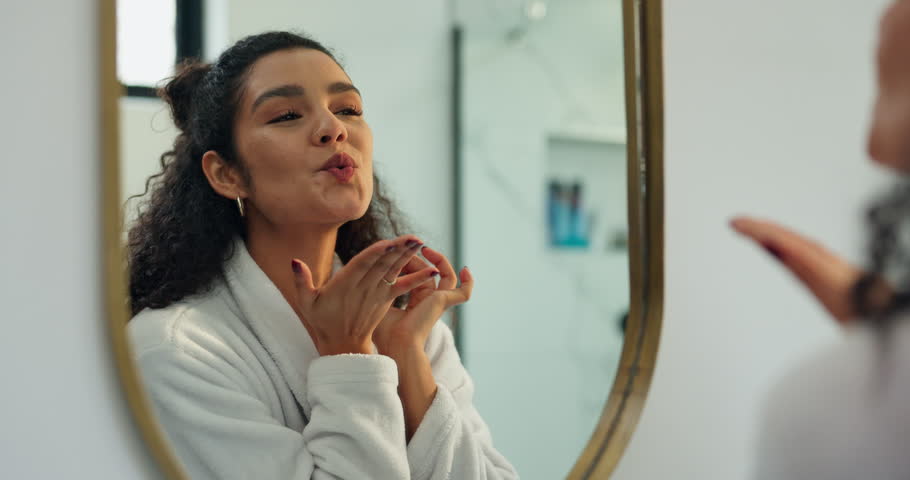 Happy woman, reflection and beauty with mirror in bathroom for skincare, self care or love in home. Female person, satisfaction and blowing kiss with smile for grooming, hygiene or facial in house