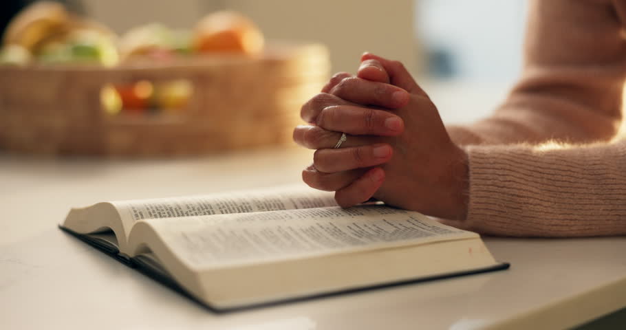Prayer hands, reading and bible study in home, faith and scripture review for spiritual guide with hope. Person, book and knowledge for Christian religion, story and holy literature for God at house