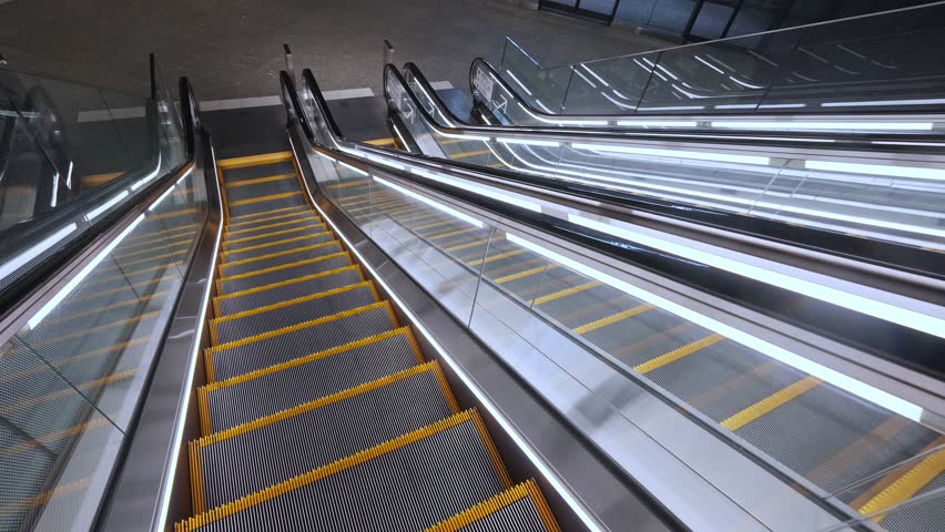 Multiple contemporary escalators with bright lighting, symbolizing movement and urban transit in a busy Tokyo setting.