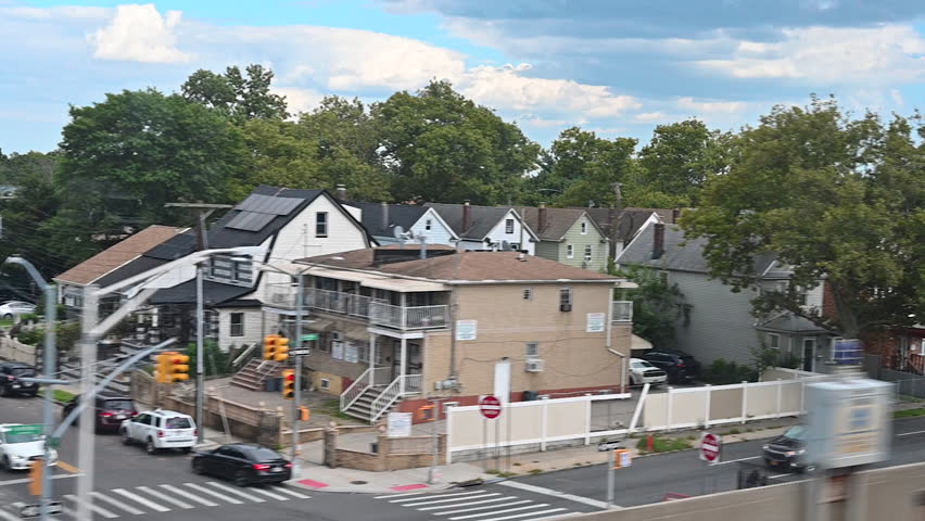 New York City,United States,August 22,2024.The outskirts of New York seen from the Air Train as it travels toward JFK Airport.A continuous succession of low,detached houses and a few trees.Slow motion
