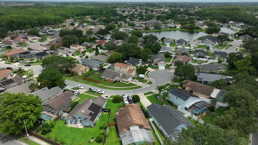 Villas and modern single family houses in luxury district of Orlando, FL. Aerial top down flyover. Parking cars on street cul du sac. Sunny summer day. Lake in background.