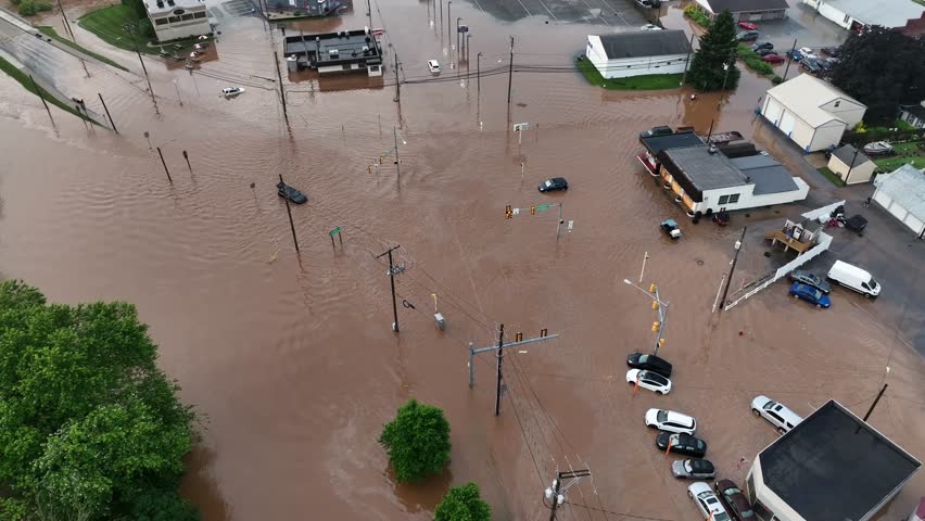 Flooded neighborhood with dirty brown water in United States. Aerial top down shot. Flood river stream covers streets and roads in small town America, USA. Nature catastrophe in American residential