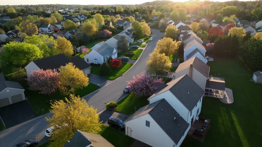 Modern American neighborhood with animated sold tags over rooftops. Aerial view of expensive and popular housing market. Golden hour sunset during spring.