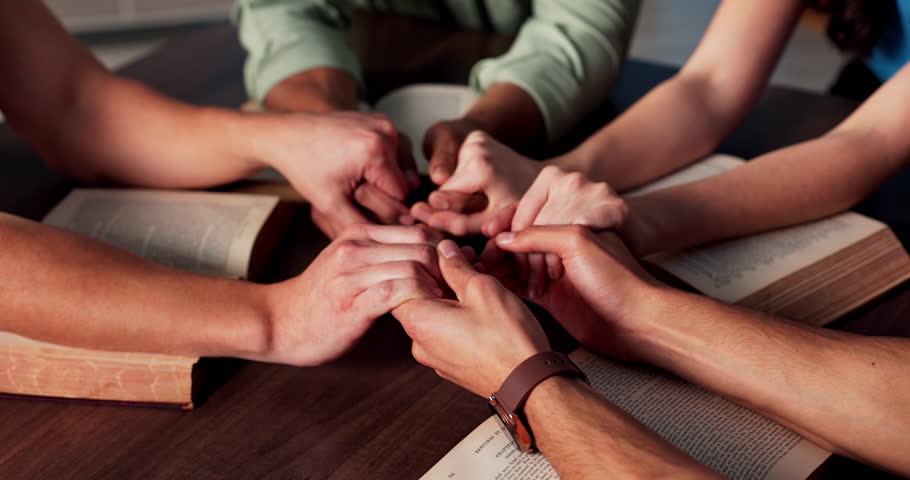 Praying, holding hands and people with bible, church and Christian with faith in God or holy spirit. Prayer group, together and worship with scripture in chapel, table or belief for religion or Jesus