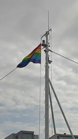Rainbow pride flag waving in the wind under a bright blue sky, symbolizing love, diversity, and LGBTQ pride. Perfect for celebration and equality concepts.