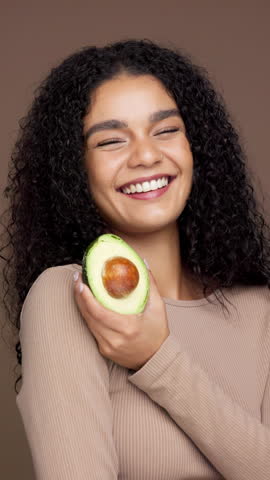Avocado, happy and face of woman in studio for skincare, natural cosmetics and facial care. Brown background, dermatology and portrait of person with fruit for vitamin E, organic benefits and beauty