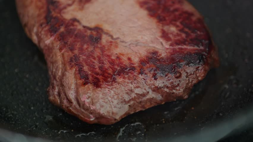 Juicy steak searing in a hot pan, ready for a delicious dinner experience.
