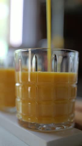 Pouring fresh orange juice into a glass at a cozy kitchen setting
