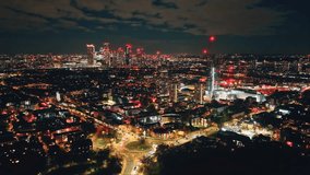 Breathtaking aerial view of London at night, highlighting the vibrant glow of Canary Wharf amidst a bustling urban landscape filled with illuminated buildings and dynamic energy. Drone flight footage - Powered by Shutterstock - Get 15% off with code: PIKWIZARD15