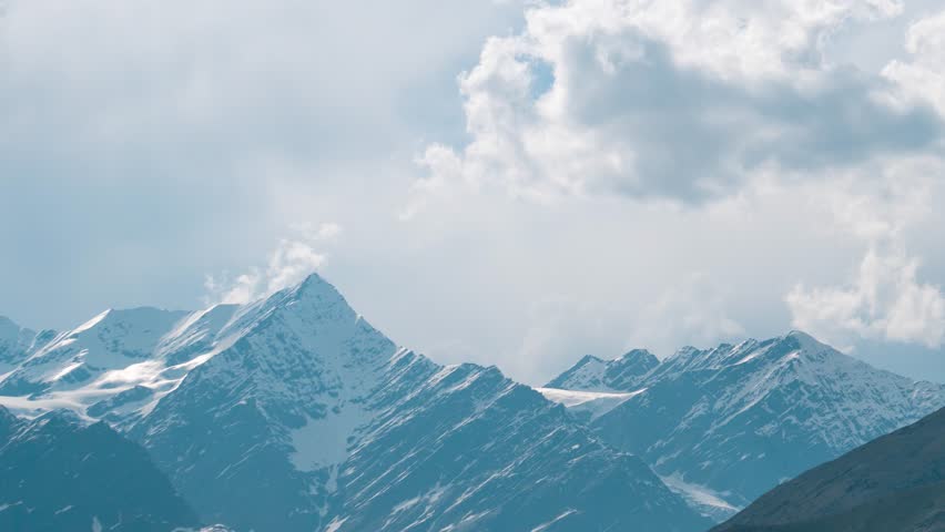 4K Time lapse of clouds moving over snowy mountains and sunrays moving at Lahaul, Himachal Pradesh, India. Snow and glacier on high Himalayan peaks. Monsoon clouds background. Nature landscape.