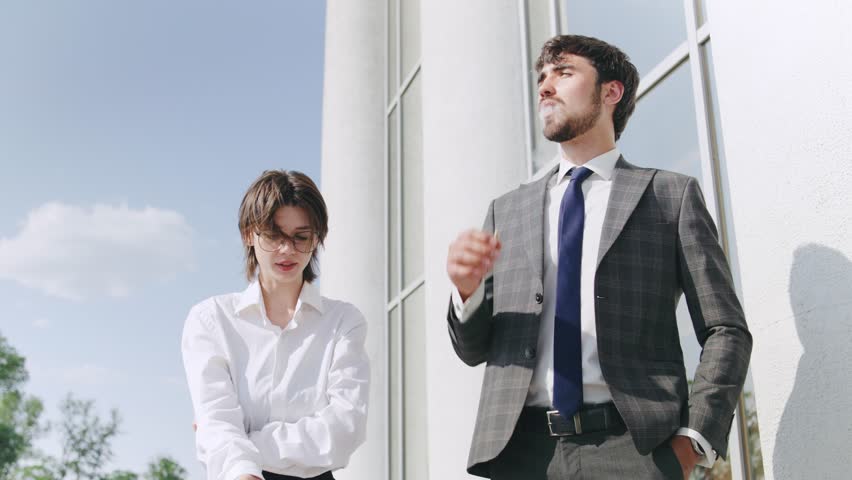 Business professionals smoking cigarettes engage in discussion outside modern office building during daytime, showcasing collaboration and networking in a corporate environment
