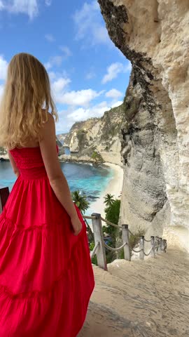 Woman exploring scenic cliffs and turquoise shore of Diamond Beach on Nusa Penida Island, Bali, Indonesia. Ideal for themes of travel, adventure, freedom, and tropical beauty.