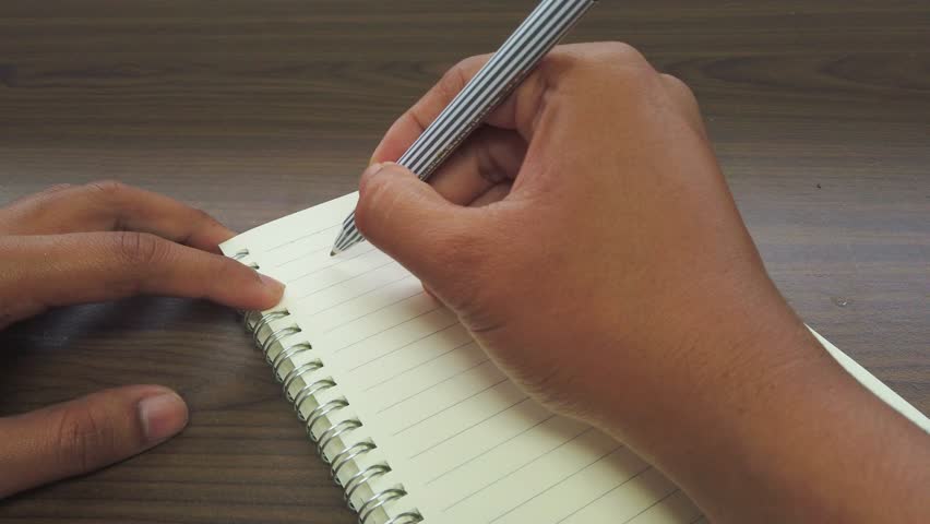 hand of Asian Man writing August Sign on the notebook.