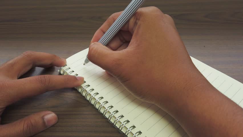 Hand of Asian Man writing November title on a notebook.