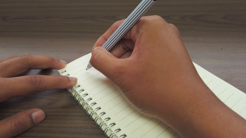 Asian men writing October title on a notebook.