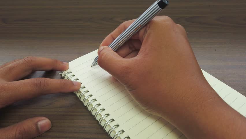 Asian man writiing September as a title on a notebook.