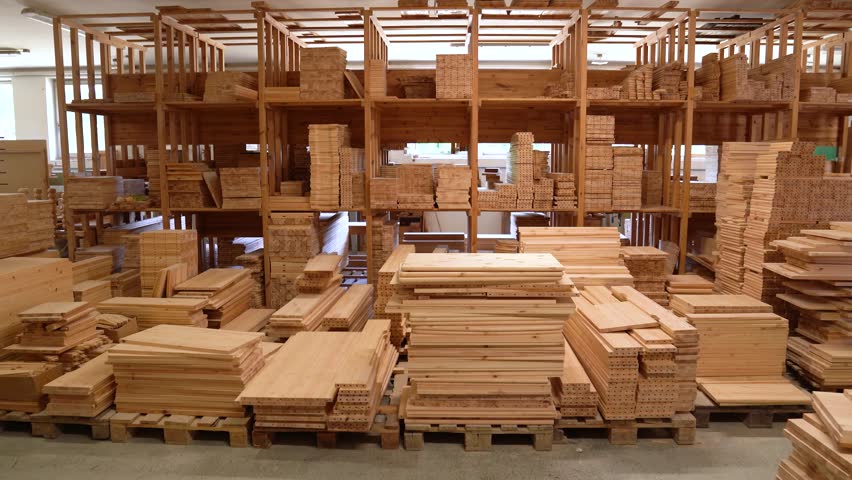Stacks of processed timber boards stored in wooden warehouse interior.