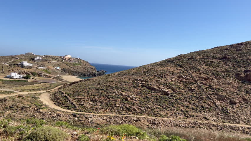 A scenic drive on a dirt road reveals a tranquil beach as the view opens from behind a rugged hillside. Perfect for destination promos, travel vlogs, digital detox, and travel documentary projects.