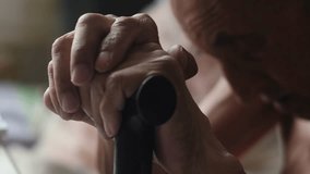 an elderly man sits holding a walking stick with his head down, emotions of old people, a grandfather with a walking stick sits thoughtfully - Powered by Shutterstock - Get 15% off with code: PIKWIZARD15