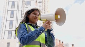 Construction worker uses megaphone to direct team at building site during daytime in urban area - Powered by Shutterstock - Get 15% off with code: PIKWIZARD15