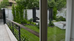 Wide-angle shot of a backyard showcasing a lush lawn, black pergola seating area, ornamental shrubs, and tall green conifers. The foreground includes lava rocks and the background reveals  - Powered by Shutterstock - Get 15% off with code: PIKWIZARD15