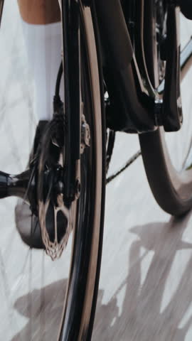 Sportsman in black sneakers rides bicycle along track closeup. Man athlete spins modern vehicle pedals enjoying active leisure on sunny track slow motion