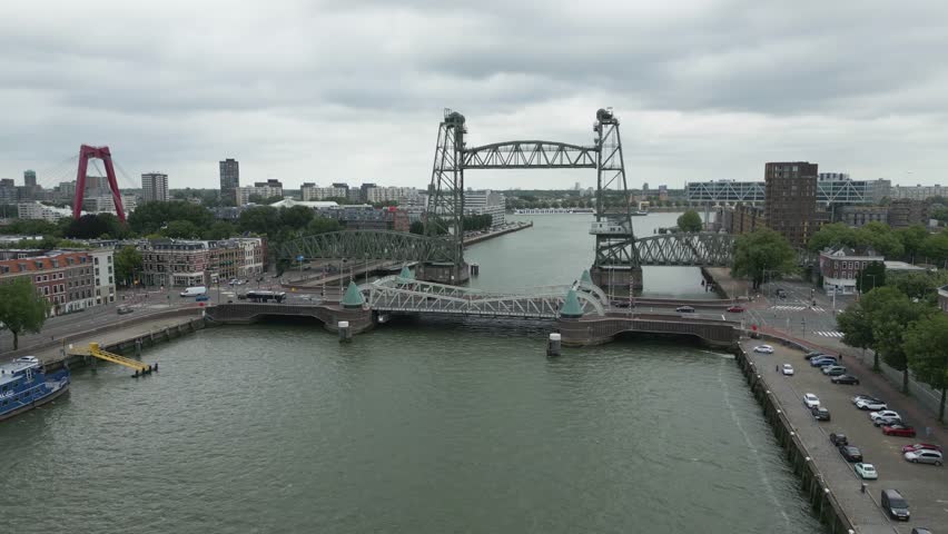 Drone footage of De Hef, a famous vertical lift bridge in Rotterdam, with the city skyline and the Willemsbrug in view.