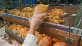 selecting freshly baked bread from bakery display case. baker's gloved hands carefully place a freshly baked, crusty loaf of bread, sprinkled with seeds, into a warm display case filled artisan bread - Powered by Shutterstock - Get 15% off with code: PIKWIZARD15