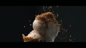 Captivating slow-motion close-up showcases golden toasted coconut flakes delicately raining down onto luscious scoops of creamy vanilla ice cream in a crisp waffle cone, set against a dark background - Powered by Shutterstock - Get 15% off with code: PIKWIZARD15
