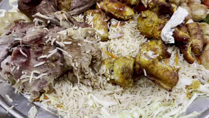 Platter loaded with rice, chicken, lamb, mutton, Large food platter with rice and meats, Platter of rice topped with mixed meats, Big food platter with rice and meats, 4K VIDEOS.
