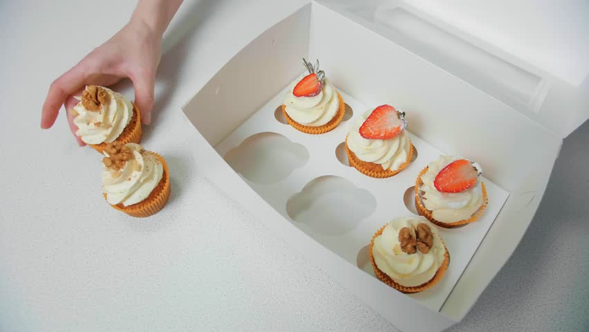 Overhead: Hands Arranging Freshly Baked Cupcakes with Strawberry and Walnut Toppings into White Gift Box. Bakery Packaging.