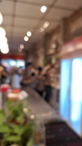 Blurred background of a coffee shop, with people walking and interacting with the barista, showcasing a vibrant urban atmosphere. Blurred interior background.