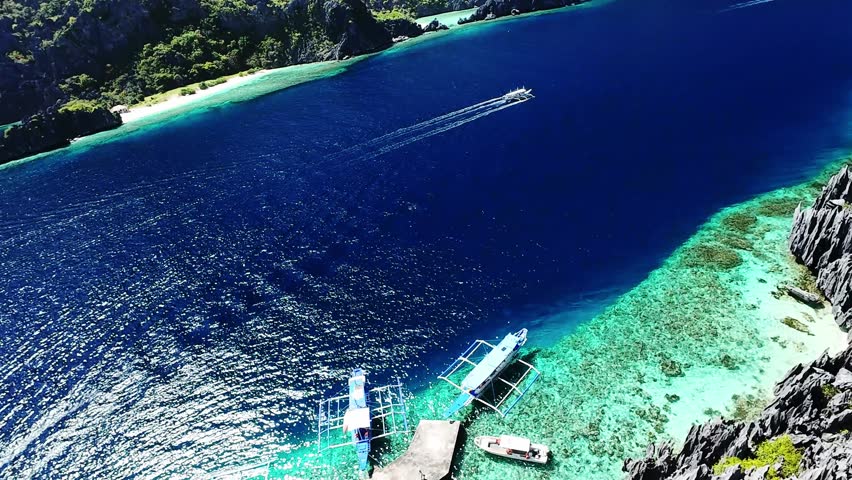 Turquoise reef and docked boats in El Nido, Palawan, Philippines from high aerial angle Aerial top view of boats docked along turquoise reef in El Nido, Palawan, Philippines with deep blue sea and cle