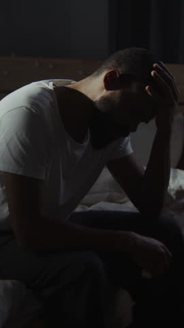 Black bearded man gives up at depression enhancement period in bedroom. African American male avoids friends during mental illness attack at home