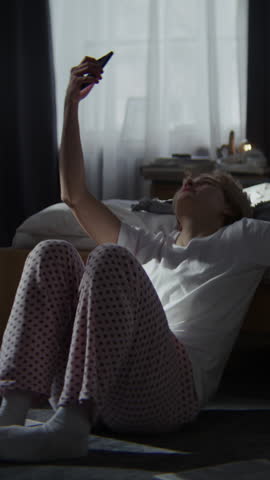 Woman makes selfie for social media suffering form hidden depression. Lady wearing pajamas surrounded by books experiences deep emotional distress
