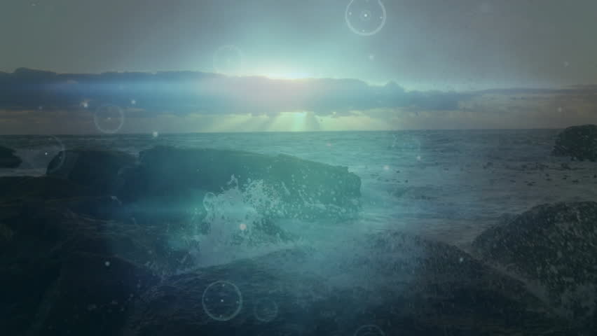 Rising sun peeking over horizon causing waves lapping rocks while HUD arcs and lens flares scanning. Seascape, sunrise, digital overlay, atmospheric, tranquil, cinematic, futuristic