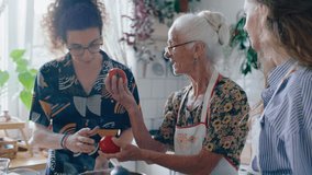Elderly grandmother giving young grandson and granddaughter fresh ripe tomatoes to smell and explaining how to cook them in kitchen at home - Powered by Shutterstock - Get 15% off with code: PIKWIZARD15