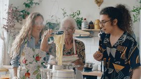 Elderly grandmother using kitchen tongs to serve freshly boiled pasta onto plate, smiling and chatting with two young grandchildren during family cooking time at home - Powered by Shutterstock - Get 15% off with code: PIKWIZARD15
