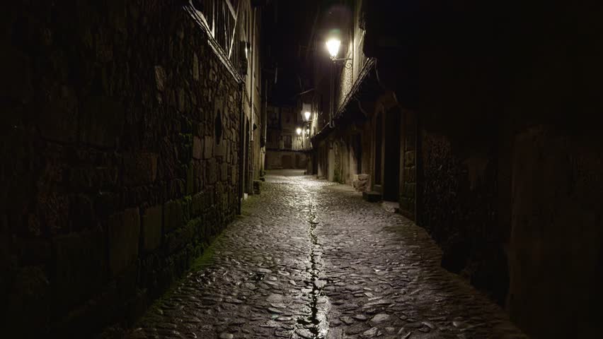 Empty night street in La Alberca with stone walls and lantern light. Ideal for moody travel, history, or European village atmosphere.