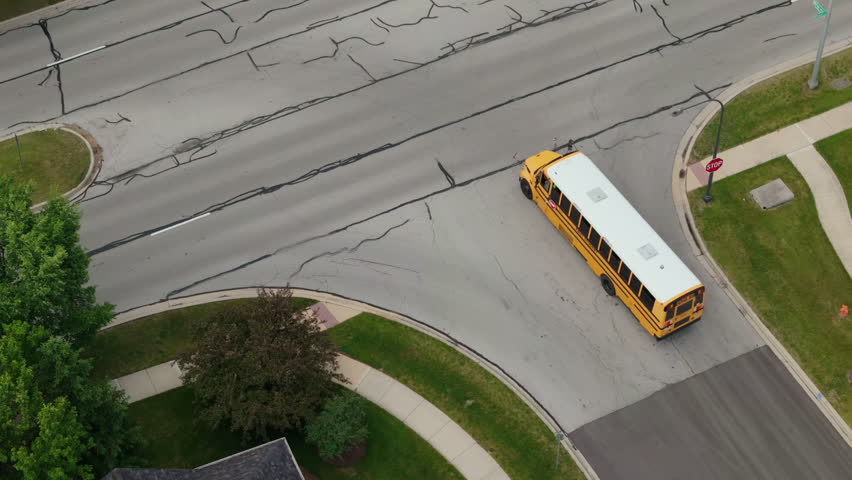 Aerial shot of yellow school bus driving on suburb street