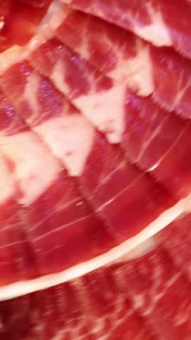 Authentic spanish delicacy rotating slowly, revealing intricate marbling and deep red hues of premium iberian ham against clean background