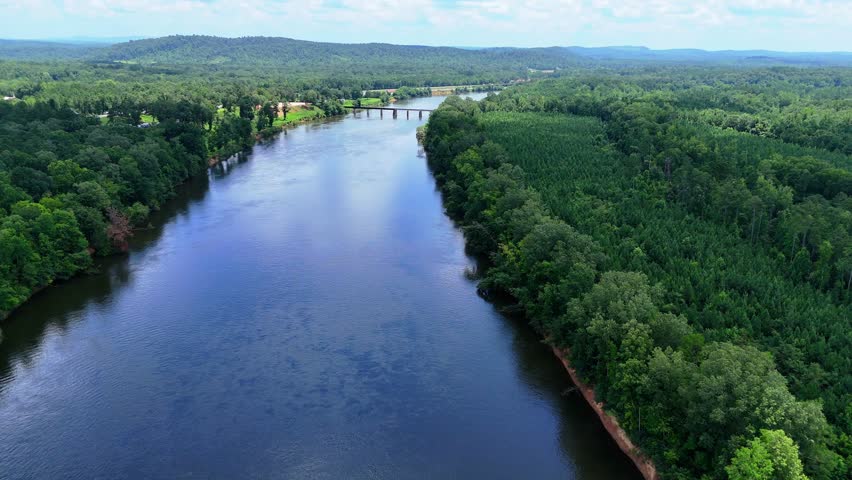 Peaceful aerial drone footage of the Coosa River near Ohatchee, Alabama, showcasing the natural beauty of the river as it winds through dense trees and untouched wilderness. 