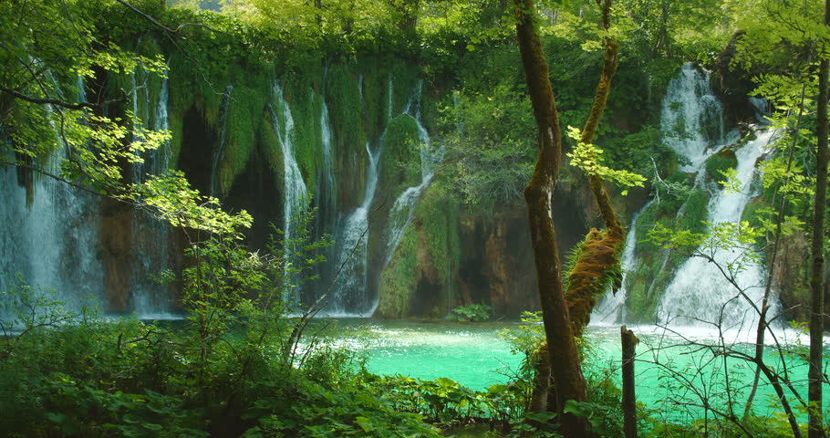 Scenic view of lush waterfalls cascading into a turquoise lake in Plitvice Lakes National Park Croatia